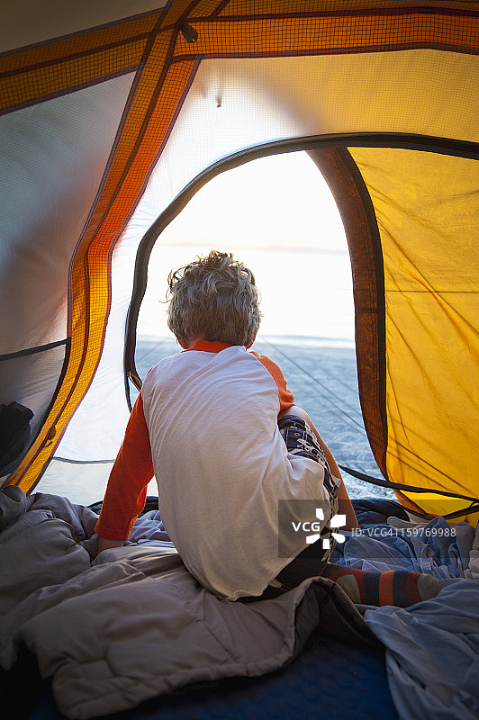海滩营地的清晨，男孩在帐篷外观望图片素材