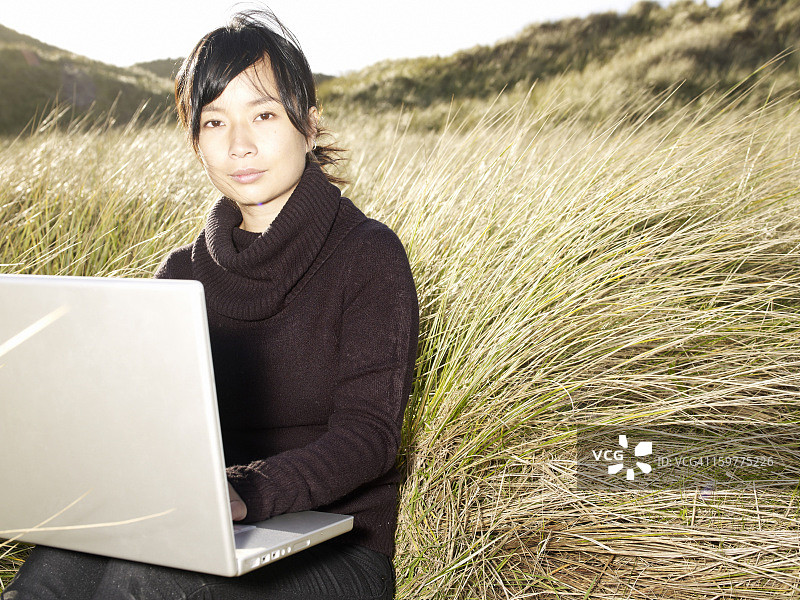 在草地上使用笔记本电脑的女人图片素材