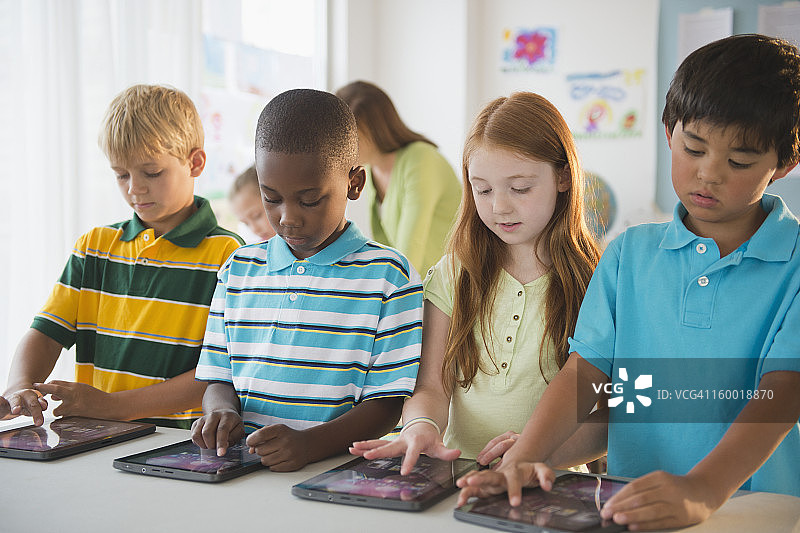 8-9岁的小学生与女老师一起使用电脑图片素材