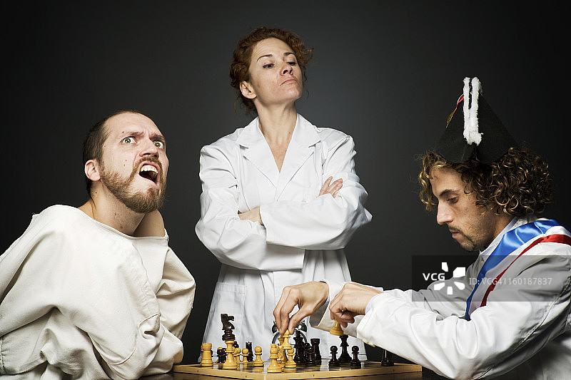 医疗专业人员监督一场象棋比赛。一名玩家穿着紧身夹克，另一名玩家穿着花哨的礼服图片素材