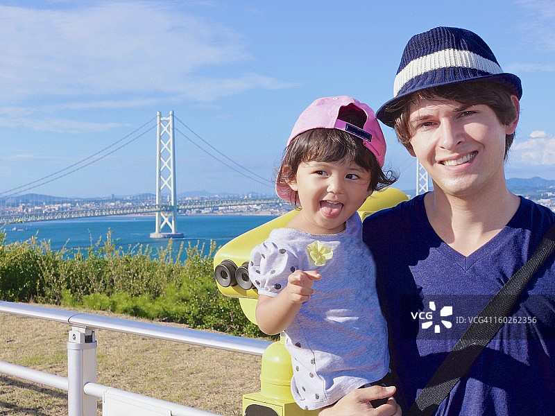 父亲和年幼的女儿在桥前合影图片素材