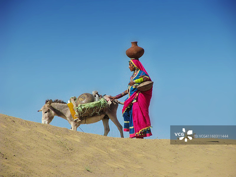 妇女在沙漠中取水图片素材