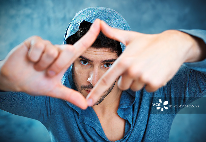 透过手指框架观看的年轻男人图片素材