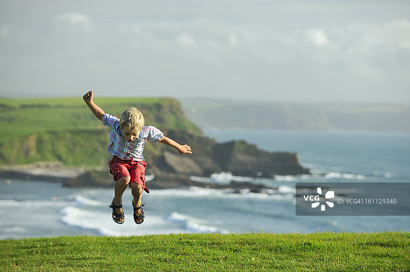 男孩在悬崖顶上跳跃图片素材