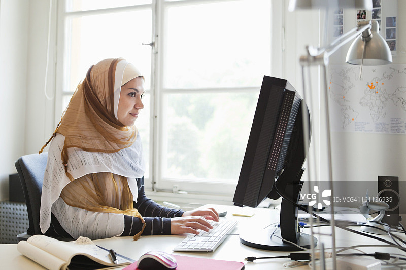 戴头巾的女人在电脑前工作图片素材