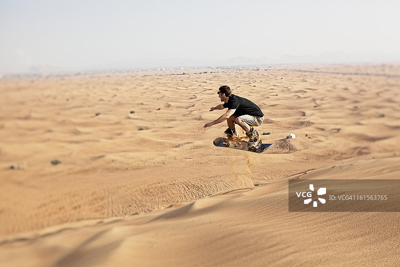 在沙漠中玩沙滩滑板的男人图片素材