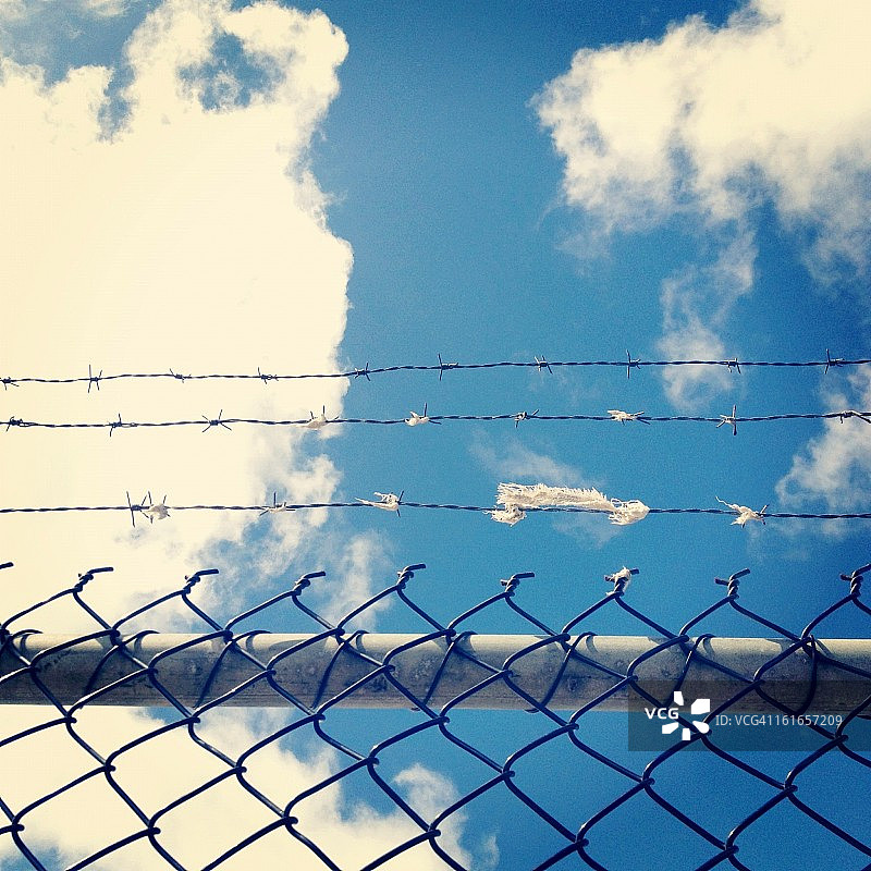 多云背景下的带刺铁丝网图片素材