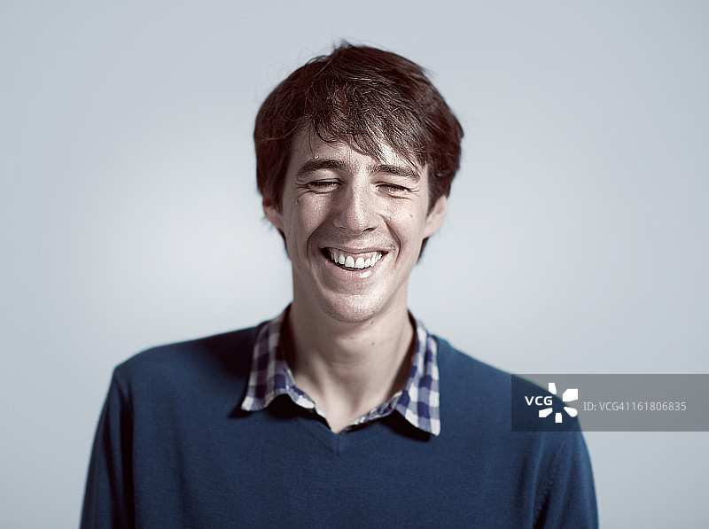 男子身穿蓝色V领套头衫大笑图片素材