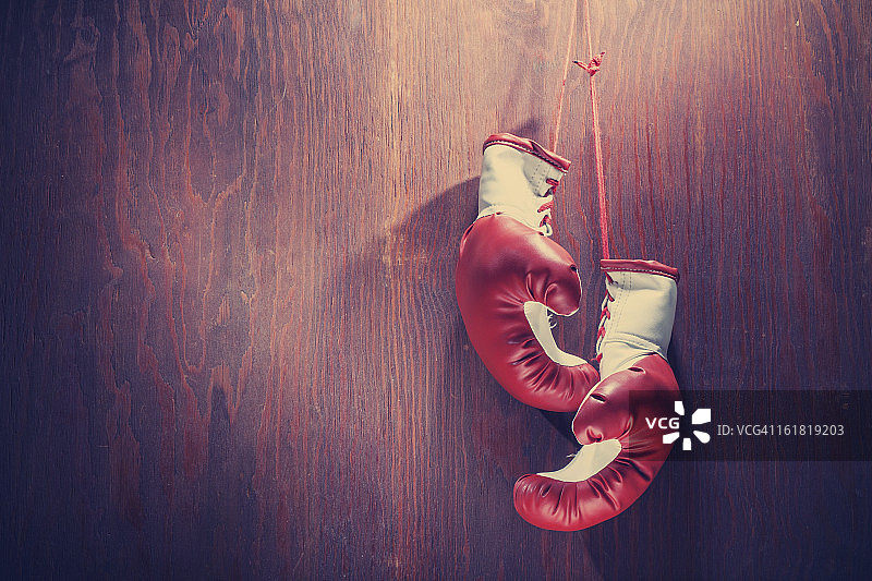 悬挂在木质背景上的红白色拳击手套图片素材