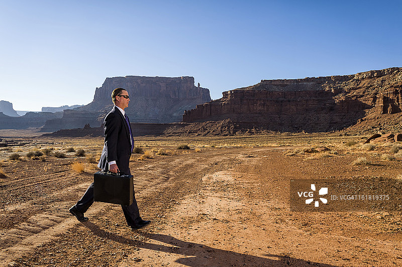 走过荒凉道路的商务男士图片素材
