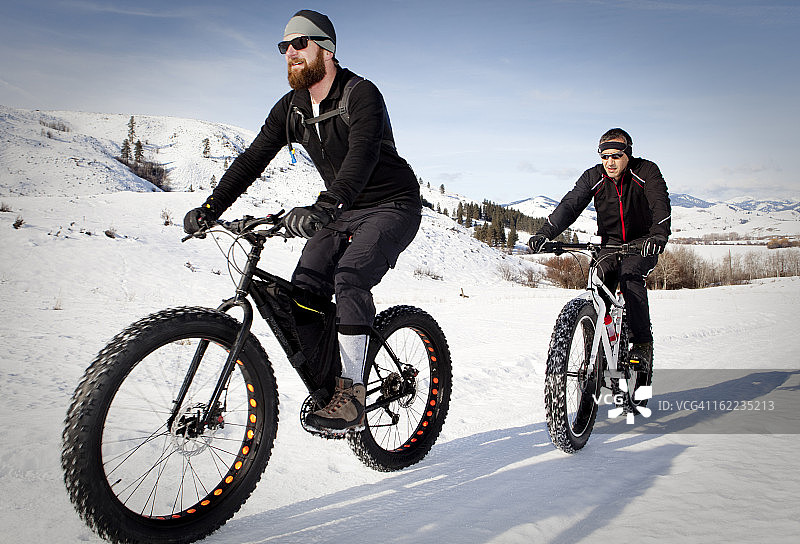 两个男人骑着雪地摩托在山路上行驶图片素材