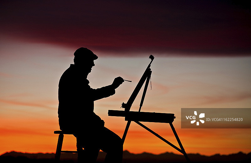 日落时用画架绘画的男人剪影图片素材