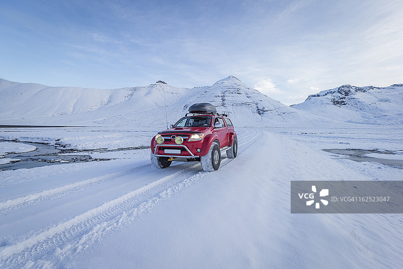 在冰岛新鲜雪地上行驶的红色卡车图片素材