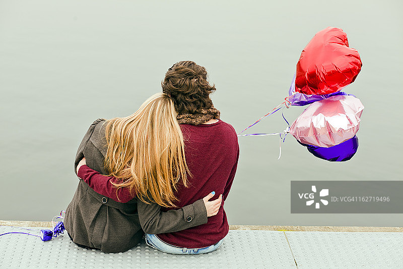 年轻情侣拥抱并拿着气球图片素材