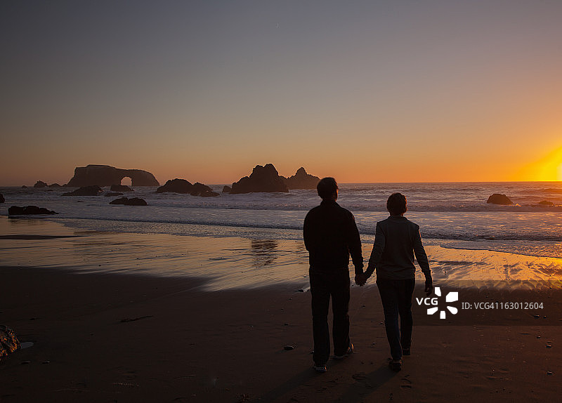 婴儿潮夫妇在日落时分的海滩上图片素材
