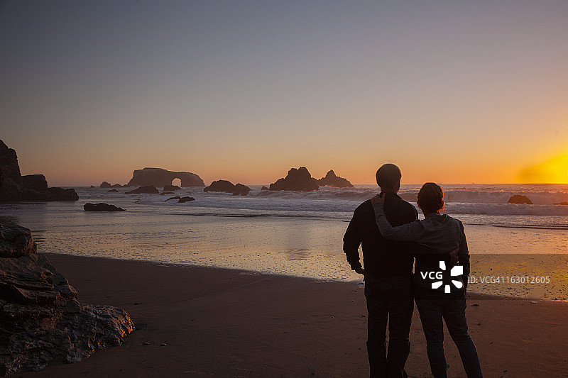 日落时分在太平洋海岸海滩上的情侣图片素材