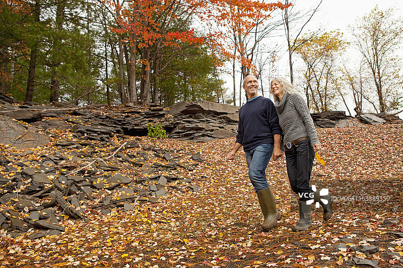 一对夫妇在秋日里手牵着手走在落叶中图片素材