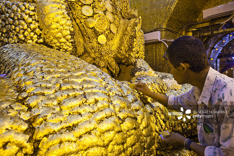 在摩诃牟尼佛塔的雕像上贴金箔图片素材