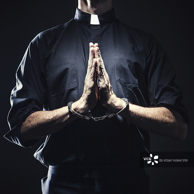 戴着手铐的天主教神父祈祷图片素材