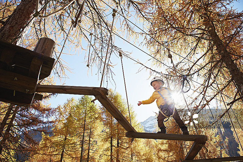 在高空绳索课程中保持平衡的男孩图片素材