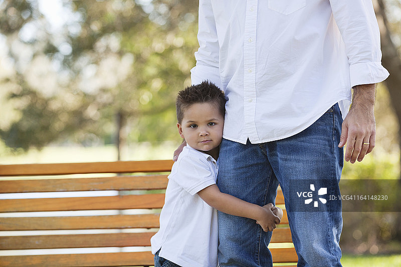 在公园里抱着父亲腿的小男孩图片素材