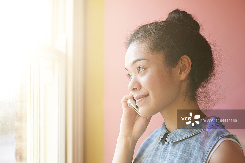 女孩在窗边打电话，粉色背景图片素材