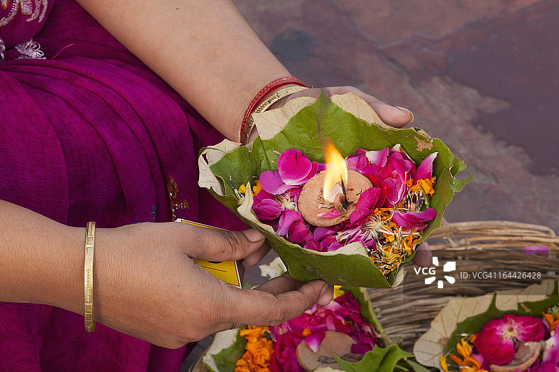 印度哈里瓦昆仑梅拉节上的祭品：信徒手持香蕉叶蜡烛和花瓣图片素材