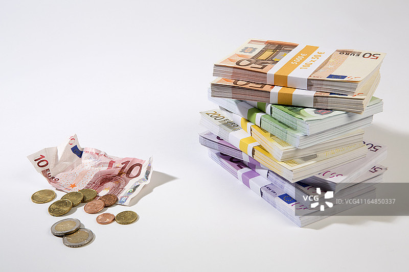 一堆大面额欧元纸币，旁边是揉皱的十元纸币和零钱图片素材