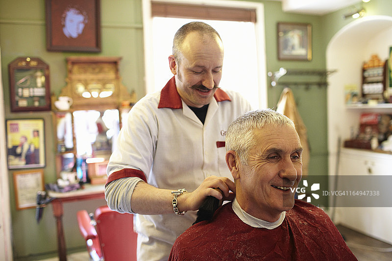 理发后理发师从顾客身上取下围裙图片素材