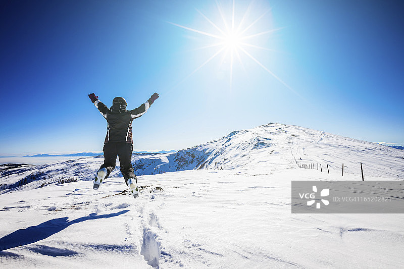 滑雪场上，快乐的滑雪女运动员在空中跳跃图片素材
