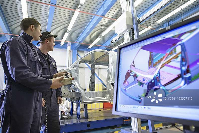 学徒在汽车厂测量车身，前景是显示器上的电脑图像图片素材