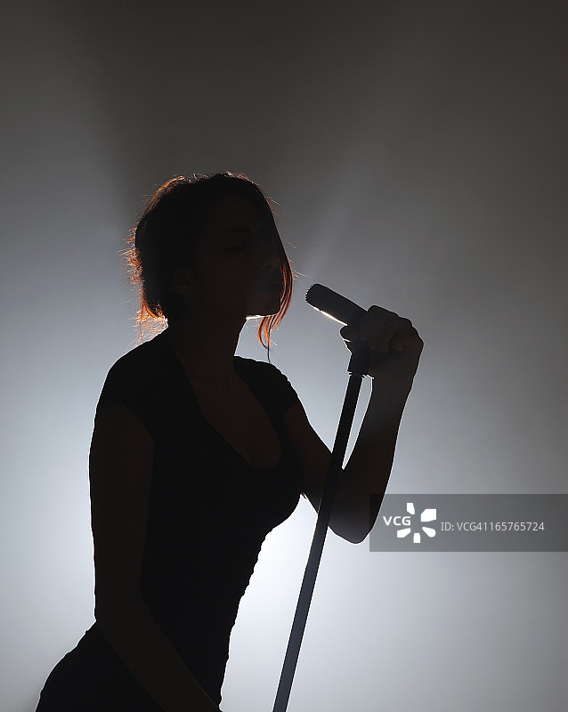 舞台上用麦克风进行背光表演的流行偶像图片素材