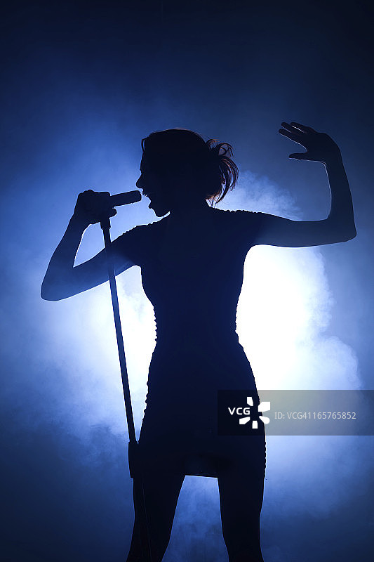舞台上用麦克风进行背光表演的流行偶像图片素材
