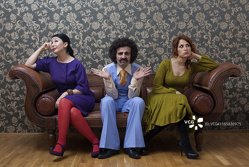 闷闷不乐的两名女人和一名男人坐在沙发上图片素材