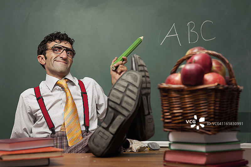 老师坐在教室里，双腿放在桌子上图片素材
