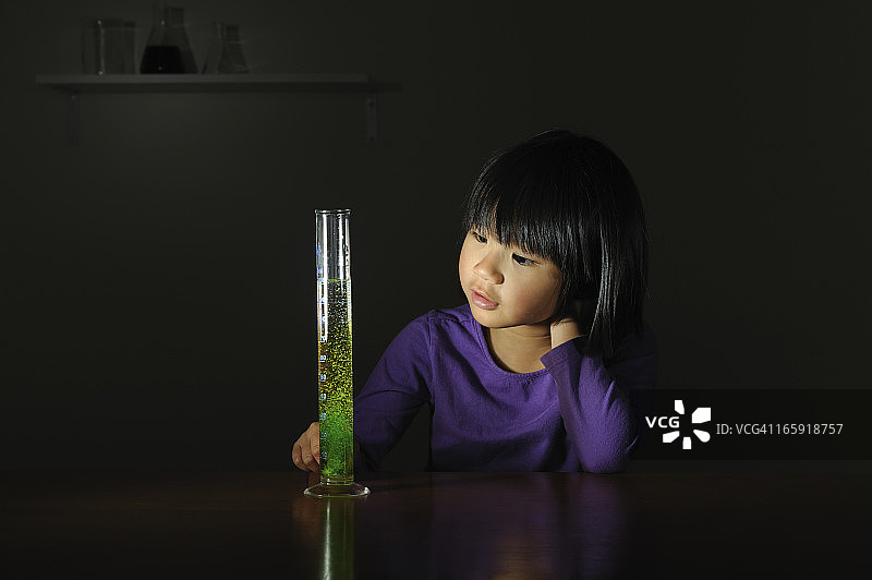 女孩看着嘶嘶作响的绿色化学物质图片素材