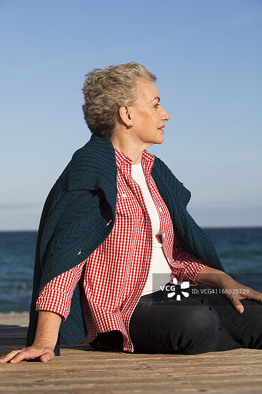 中年妇女坐在海滩的甲板上图片素材