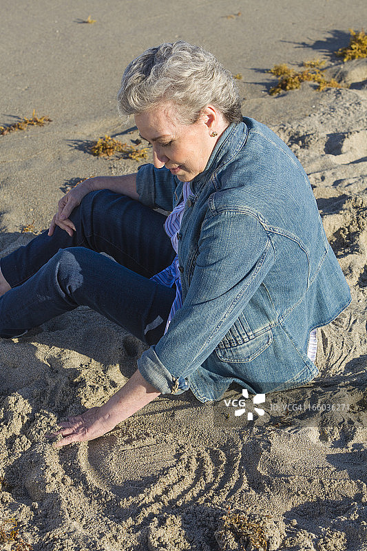 坐在沙滩上的中年妇女图片素材