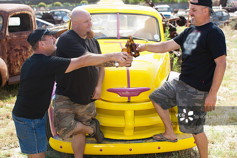 男人在彩色汽车旁喝啤酒图片素材