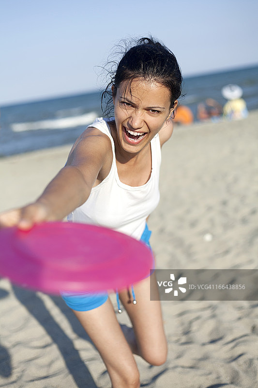 年轻女人在海滩玩飞盘图片素材