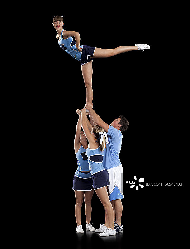 啦啦队员（16-17岁）支持单腿站立的朋友的摄影棚拍摄图片素材