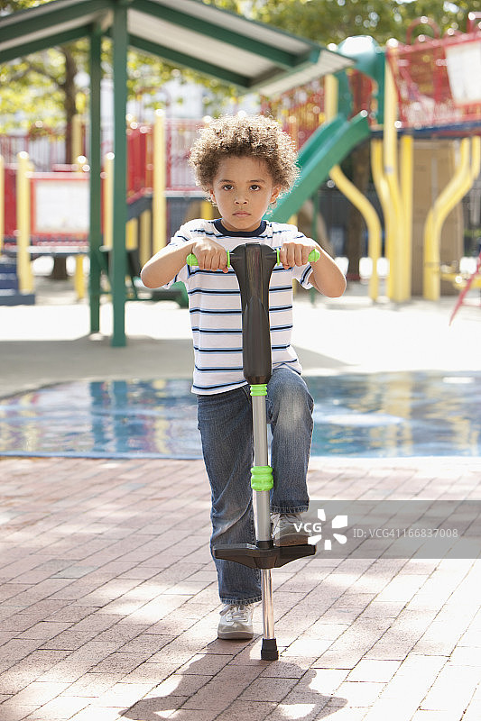混血男孩在操场上玩弹跳杆图片素材