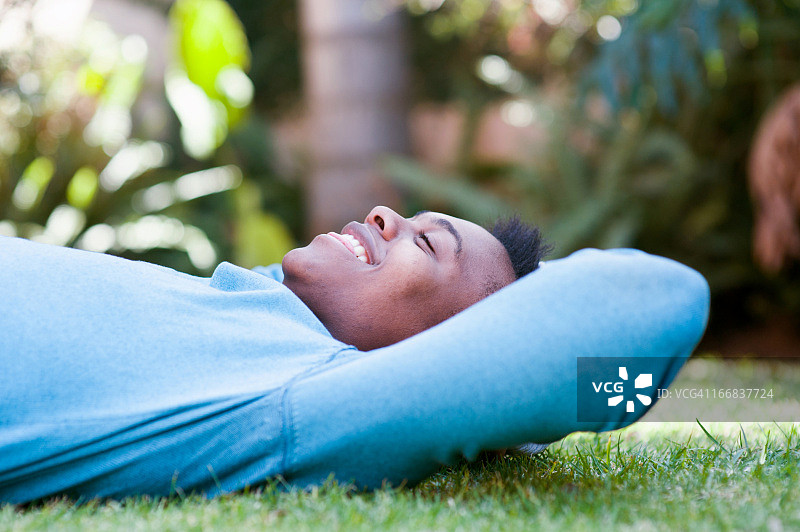 快乐的年轻男人躺在草地上，南非约翰内斯堡图片素材