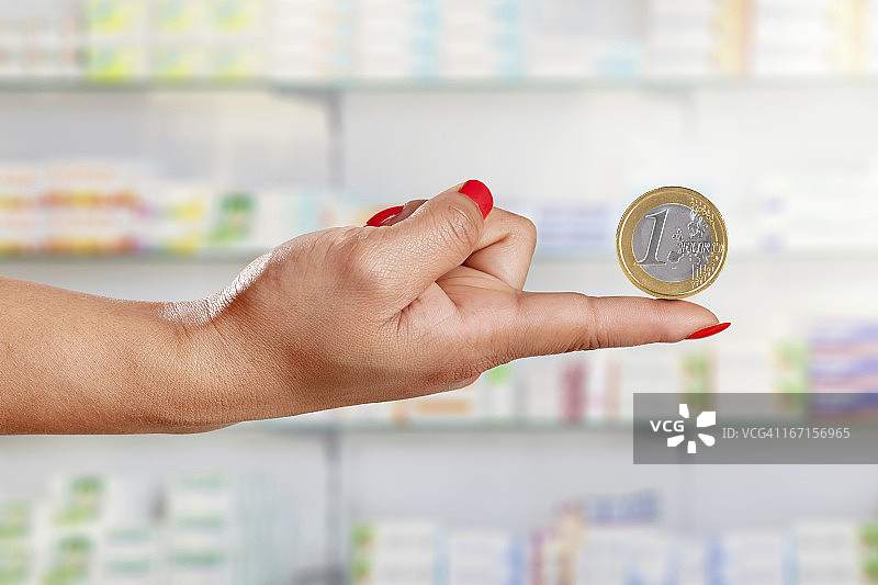 女人在药房展示一枚欧元硬币图片素材