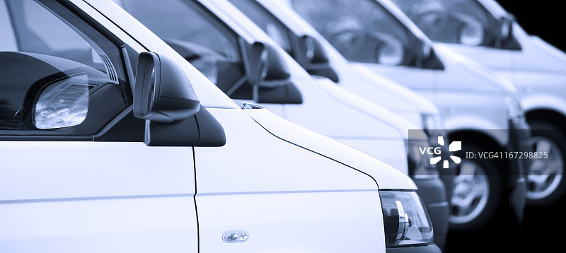 一排白色厢式货车，黑色背景图片素材