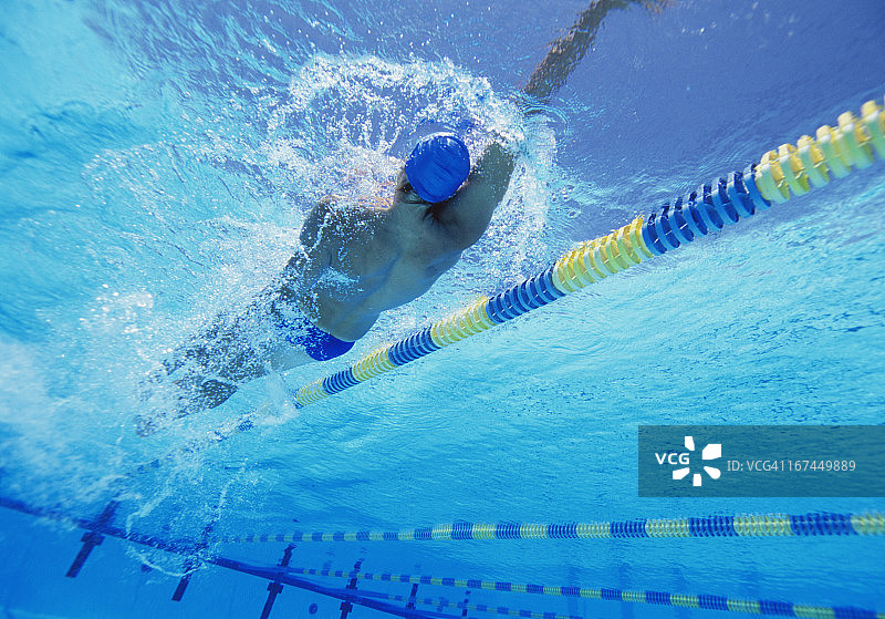 年轻的专业男运动员在游泳池里仰泳图片素材