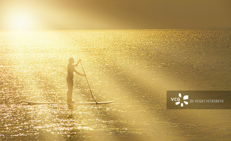 美国北卡罗来纳州纳格斯海德：日落时站立在桨板上的男人图片素材