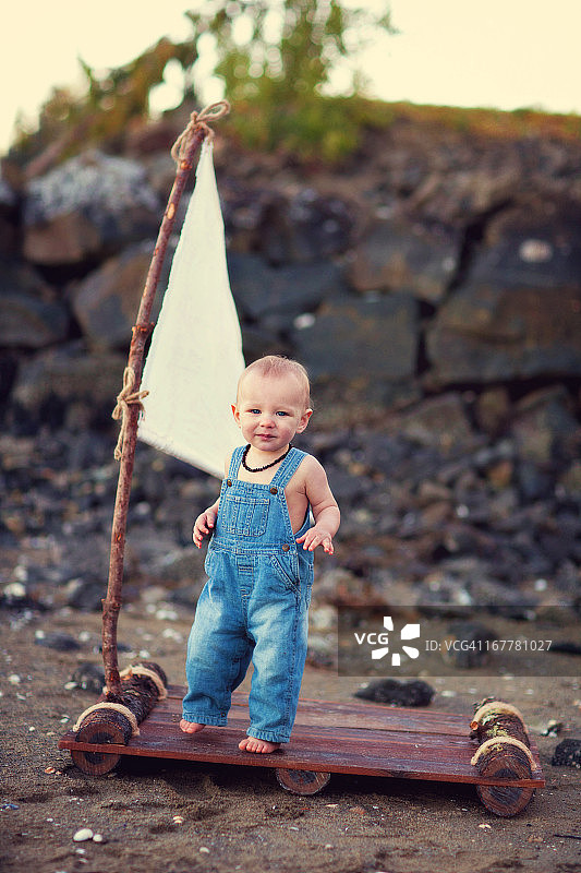 穿着背带裤坐在木筏上的男婴图片素材