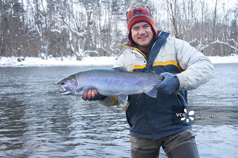 男人拿着冬天捕获的大虹鳟鱼图片素材