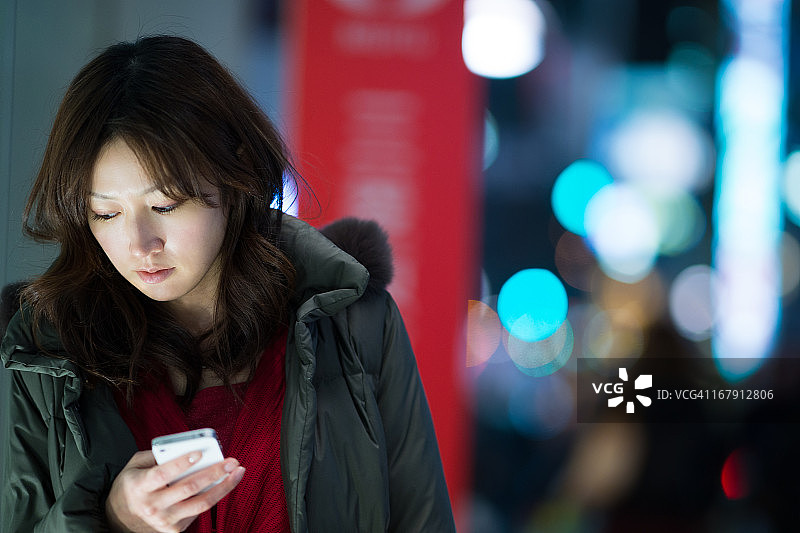 夜晚街头使用白色智能手机的女人图片素材